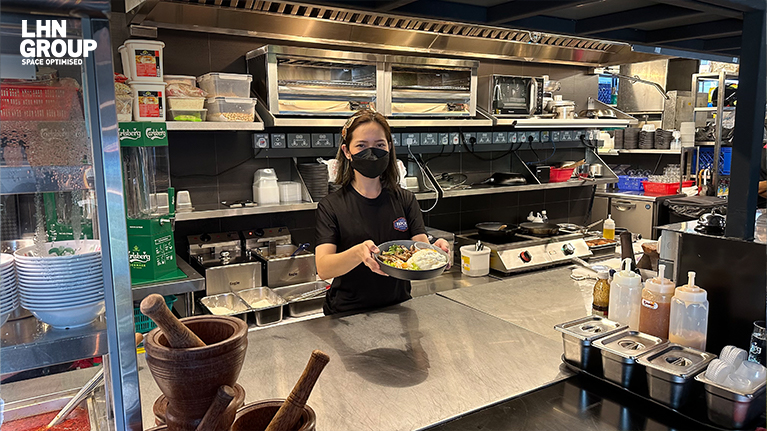 female staff holding a dish in a clean kitchen restaurant-industrial space for rent singapore